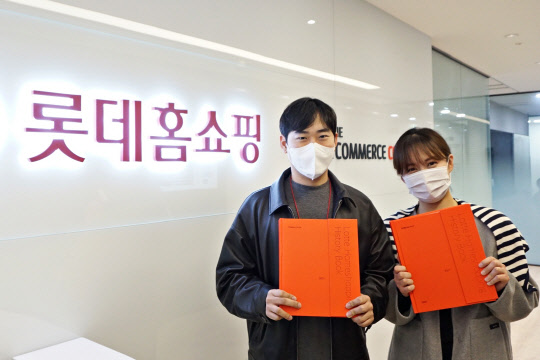 롯데홈쇼핑 직원들이 창립 20주년을 기념해 발간한 사사를 들고 포즈를 취하고 있다. <롯데홈쇼핑 제공>